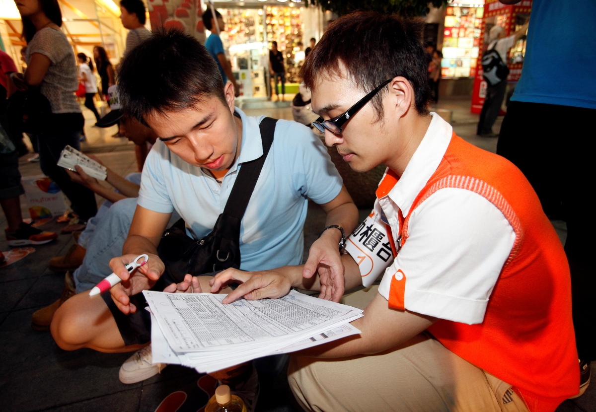 民眾湧至臺灣大哥大威秀門市現場排隊搶購,門市人員貼心為民眾(左)